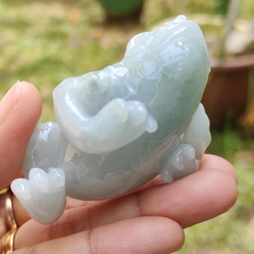 a hand holding a small jade frog