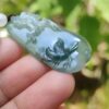 a hand holding a jade pendant