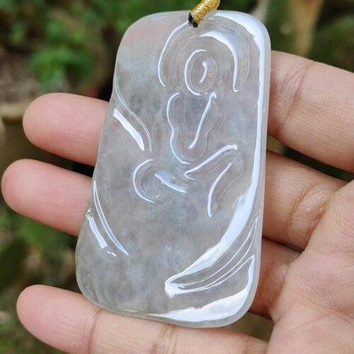 a hand holding a jade pendant