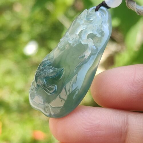 a hand holding a jade pendant