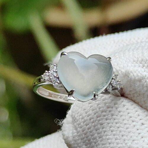 a ring with a heart shaped stone on a white cloth