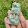 a hand holding a jade pendant