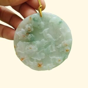 a hand holding a jade pendant