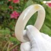a hand in glove holding a white bracelet