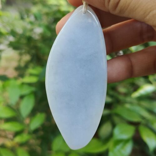 une main tenant un pendentif en pierre blanche