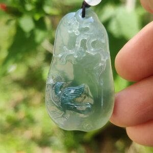 a hand holding a jade pendant