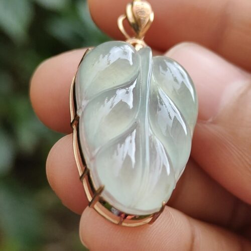 une main tenant un pendentif en jade