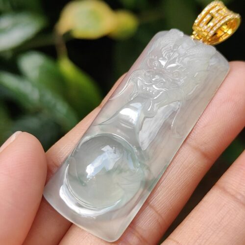 a hand holding a jade pendant