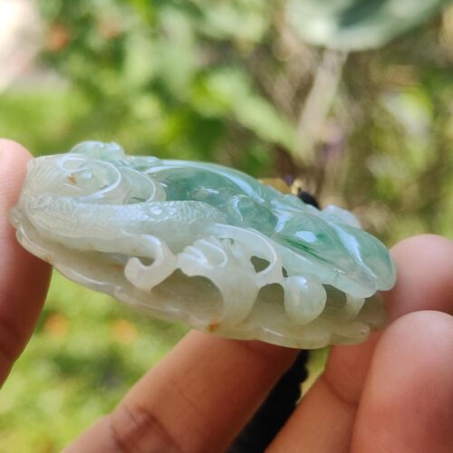 a hand holding a jade pendant