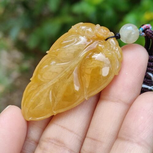 a hand holding a yellow stone pendant