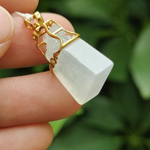 a hand holding a white stone pendant