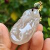 a hand holding a jade pendant