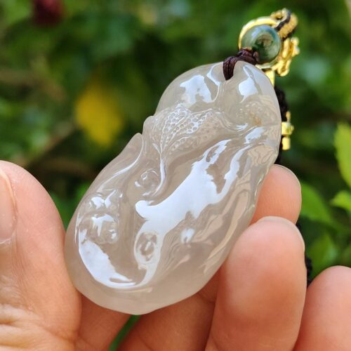 a hand holding a jade pendant
