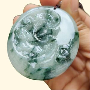 a hand holding a jade pendant