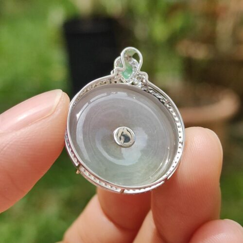 a hand holding a silver and white round object