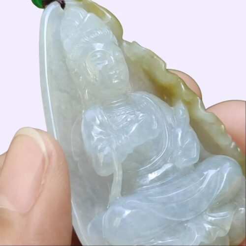 a hand holding a jade pendant