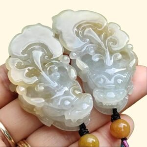 एक हाथ में जेड पेंडेंट की एक जोड़ी पकड़े हुए