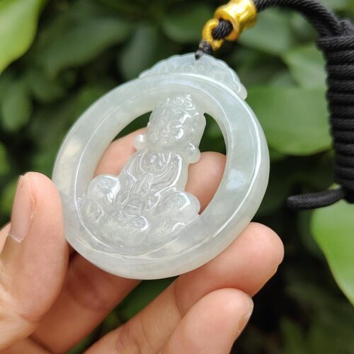 a hand holding a jade pendant