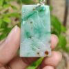 a hand holding a jade pendant