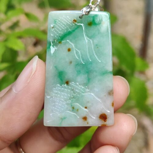 a hand holding a jade pendant