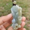 a hand holding a jade pendant