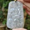a hand holding a jade pendant