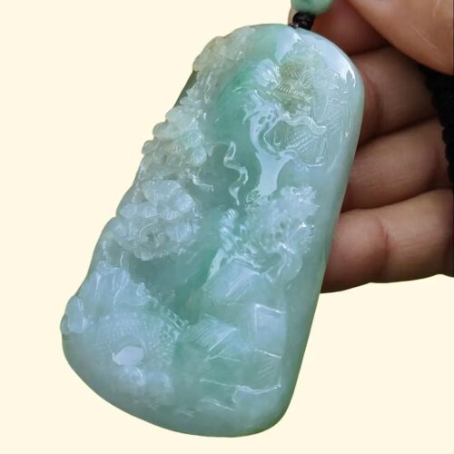 a hand holding a jade pendant