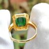 a hand wearing a gloved finger ring with a green stone