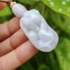 a hand holding a jade pendant