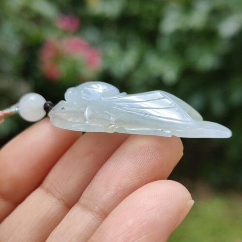 a hand holding a white bug pendant