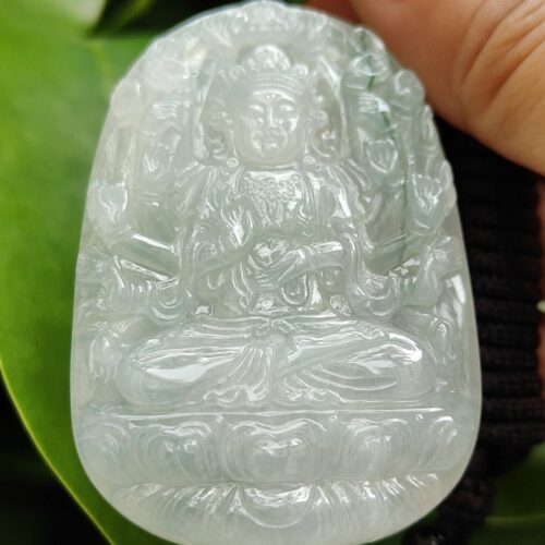 a hand holding a carved white jade
