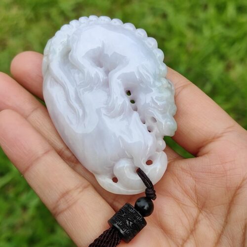 Una mano sosteniendo un colgante de piedra blanca.