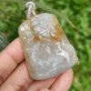 Una mano sosteniendo un colgante de jade.