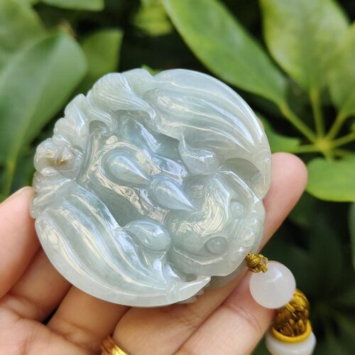 une main tenant un pendentif en jade