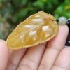 a hand holding a yellow stone pendant