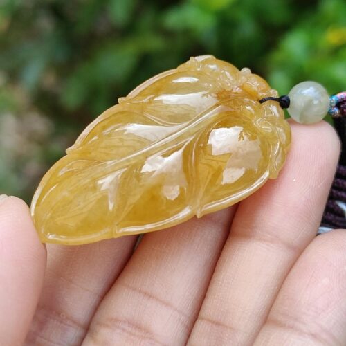a hand holding a yellow stone pendant