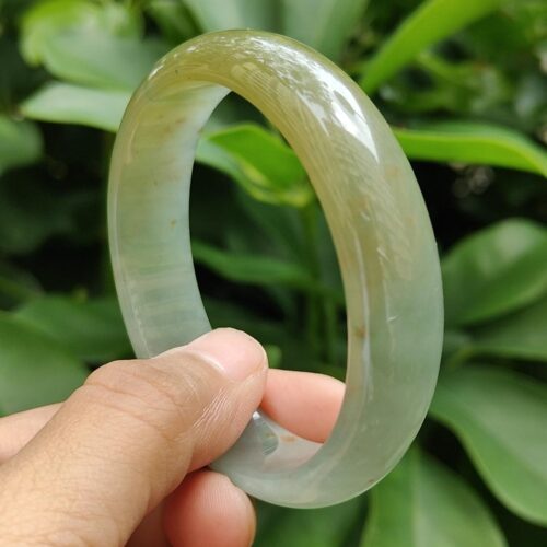 a hand holding a round green bracelet