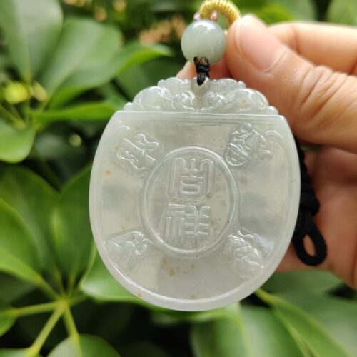 une main tenant un pendentif en jade