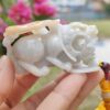 a hand holding a small white stone animal