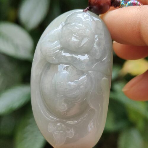 a hand holding a jade pendant