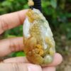 une main tenant un pendentif en jade