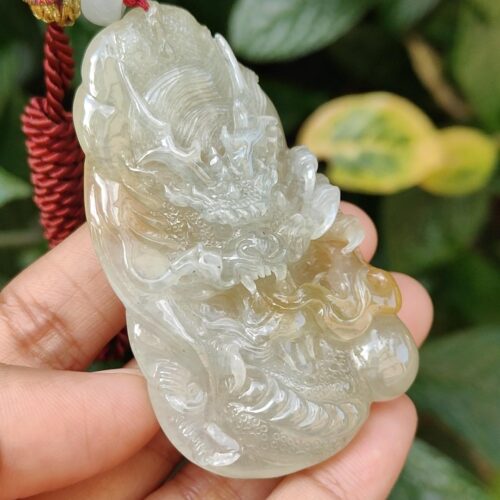 a hand holding a jade pendant