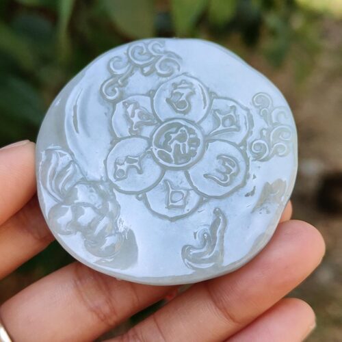 a hand holding a stone with a flower design