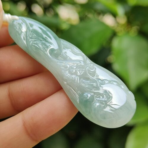 a hand holding a jade pendant