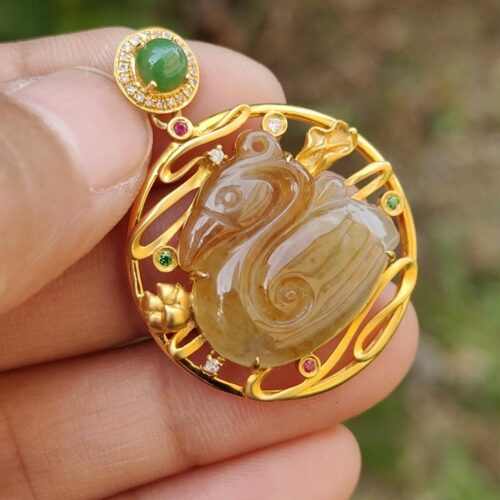 a hand holding a gold pendant with a stone in the shape of a swan