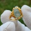 a hand wearing gloves holding a gold ring