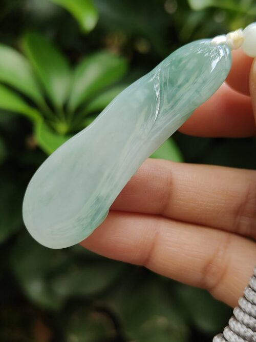 a hand holding a jade pendant