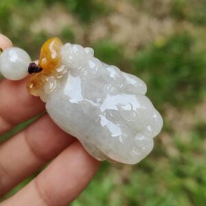 a hand holding a white and yellow bead