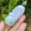 a hand holding a jade pendant