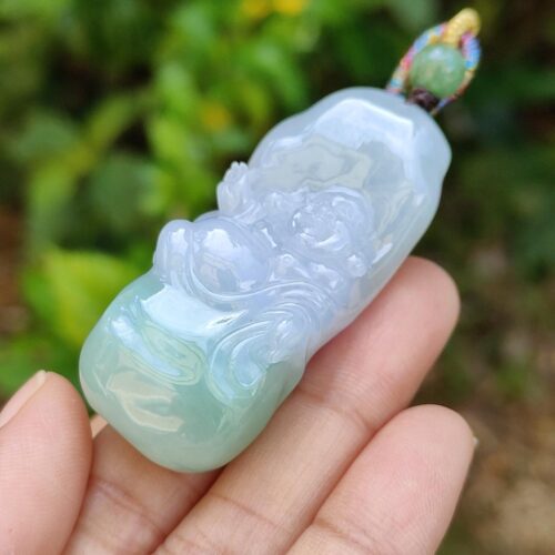 a hand holding a jade pendant
